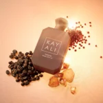 Freedom Musk Latte | 41 bottle lying on its side among coffee beans, pink peppercorns and amber crystals on a warm peach background