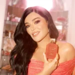 Woman with long hair holding an Eden Sparkling Lychee | 39 Kayali Eau de Parfum bottle near her face