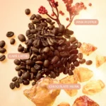 Freedom Musk Latte | 41 flat lay of coffee beans, pink pepper sprigs and amber crystals with labels Pink Pepper, Café Latte and Chocolate Musk