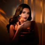 Woman holding an Invite Only Amber | 23 bottle near her face