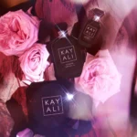 Rose Oud bakhoor jar with two perfume bottles and pink roses on oud wood