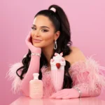 Woman in a pink fuzzy top holding a Yum Boujee Marshmallow | 81 bottle