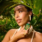 Woman holding a Maui in a Bottle Sweet Banana | 37 bottle near her shoulder among tropical leaves