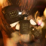 Vanilla Oud bakhoor jar with two perfume bottles, vanilla pods and an orchid on oud wood