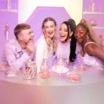 Group of women laughing around a table with pink drinks
