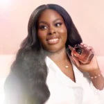 Smiling woman holding a Musk | 12 Kayali Eau de Parfum bottle