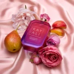 Fleur Majesty Rose Royale bottle on pink silk with a pear, peach slices and pink roses