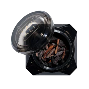 Open black Café Oud bakhoor jar filled with dark oud wood chips, lid resting beside it