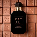 Oudgasm Chocolate Oud bottle against a wall of Kayali chocolate squares