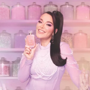 Woman with long dark hair holding a Vanilla Candy Rock Sugar | 42 bottle in front of pink shelves
