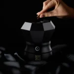 Hand placing an oud chip into the open top of the Oudgasm Diamond Bakhoor Burner