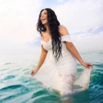 Woman in a white dress standing in turquoise sea water